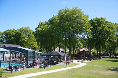 People on chairs around the outdoor pool of holiday park Camping de Norgerberg