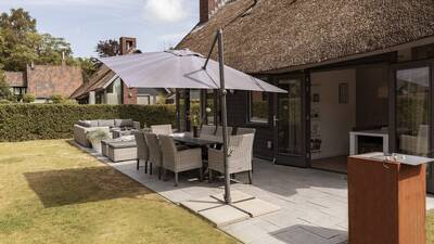 Garden with lounge set, dining table and barbecue of a holiday home at Villapark Mooi Schoorl