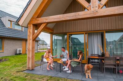 Family on the covered terrace of a holiday home at the EuroParcs Cadzand holiday park