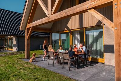 Family sitting on the terrace of a detached holiday home at the EuroParcs Cadzand holiday park