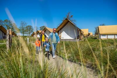 Family walks between glamping tents at the EuroParcs Zuiderzee holiday park