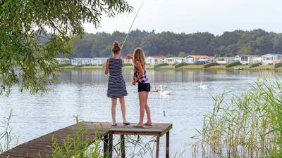 Children fishing in the Agnietenplas from a jetty at Molecaten Park De Agnietenberg