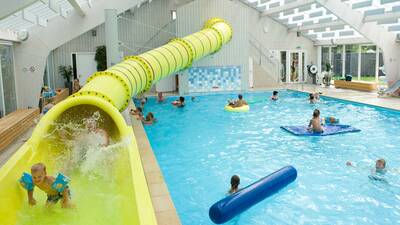 People in the indoor pool with the large yellow slide of holiday park Molecaten Park Wijde Blick