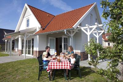 Family eats at a table in the garden of a holiday home at Roompot Résidence Klein Vink