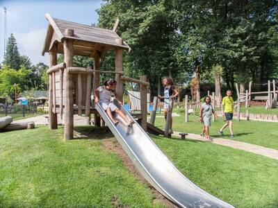 Child slides down the slide in a playground at the Topparken Landgoed de Scheleberg holiday park