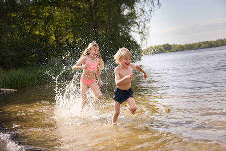 Children run through the water of the recreational lake (Victoriameer) at Lake Resort Beekse Bergen