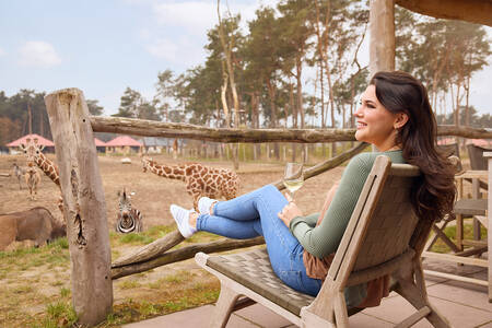Woman looks over the savannah from the terrace of a lodge at Safari Resort Beekse Bergen
