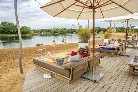 People on lounge chairs on the terrace of the Beachbar at holiday park BreeBronne