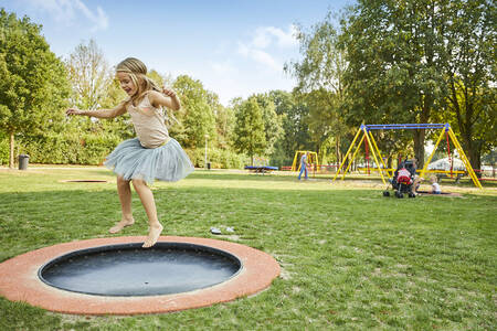 Girl jumping on a trampoline in the large playground of Buitenhof de Leistert