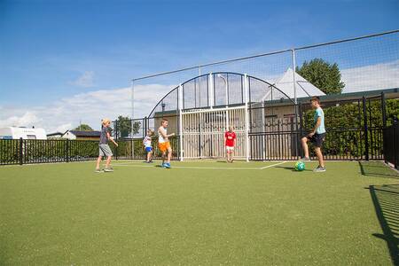 Children playing football on the football field of holiday park Camping Zonneweelde