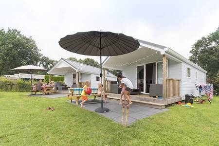 Family in the garden of a Lodge at the Camping de Noetselerberg holiday park