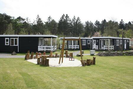 Chalets on a field with a playground at the Camping de Norgerberg holiday park