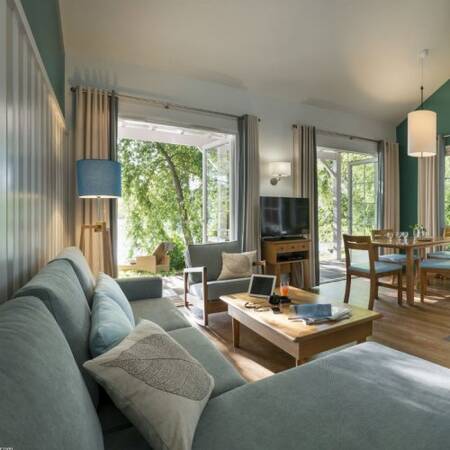 Living room with dining area and TV of a holiday home at Center Parcs Le Lac d'Ailette