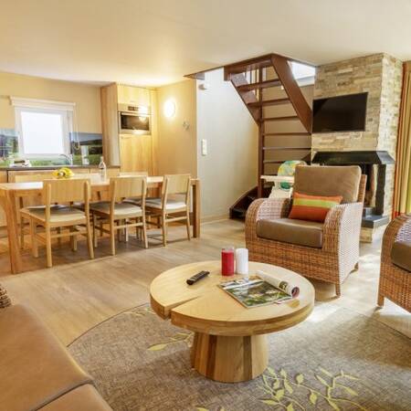 Living room with dining area and fireplace of a holiday home at Center Parcs Les Ardennes