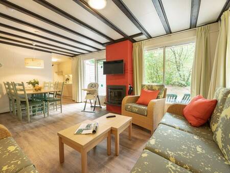 Living room with fireplace and dining area of a holiday home at Center Parcs Limburgse Peel