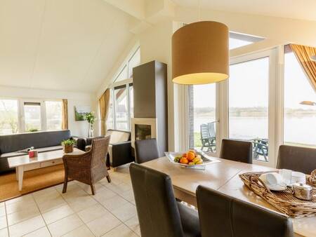 Living room with dining area and fireplace of a holiday home at Center Parcs Parc Sandur