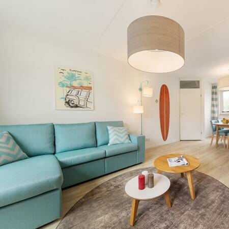 Living room with sofa and dining area in a holiday home at Center Parcs Park Zandvoort