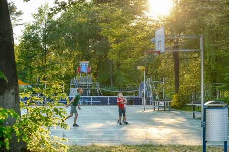 Children play basketball on the basketball court of camping site De Berenkuil