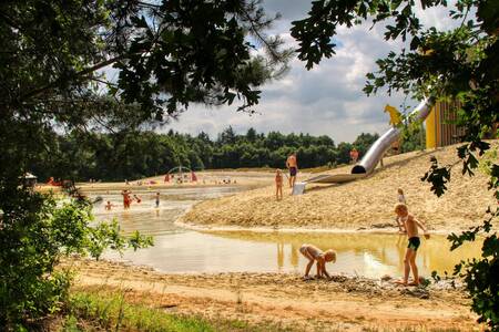 Children play around the play pond at De Berenkuil campsite in Grolloo