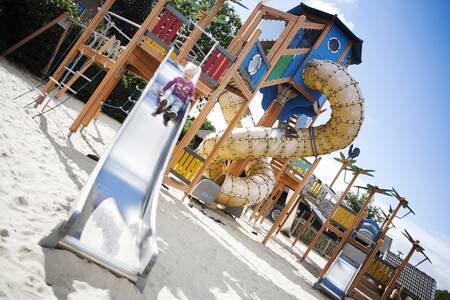 Child slides down the slide in a playground at holiday park De Boshoek
