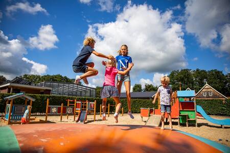 Children jump on the air trampoline in the playground of camping De Witte Berg