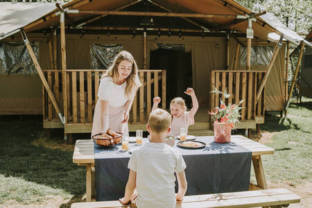 Family at a picnic table of a Lodge tent at the Dierenbos holiday park