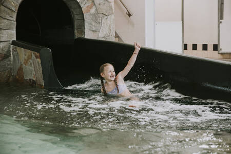 Girl comes out of the large slide of the swimming pool at the Dierenbos holiday park