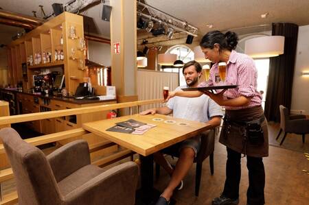 Man enjoys a Heimbacher lager in the Heimbacher Brauhaus at the Dormio Eifeler Tor holiday park