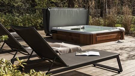 Deck chairs near a whirlpool in the garden of a house at Villapark Suitelodges Gooilanden