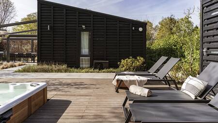 Deck chairs near a whirlpool in the garden of a house at Villapark Suitelodges Gooilanden