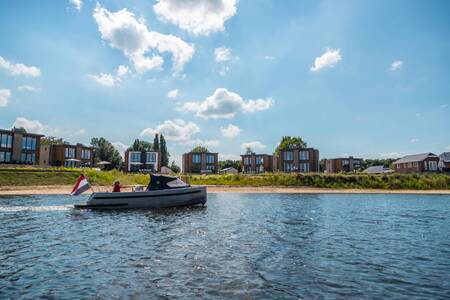 Sloop sails past the beach and holiday homes at the EuroParcs Aan de Maas holiday park