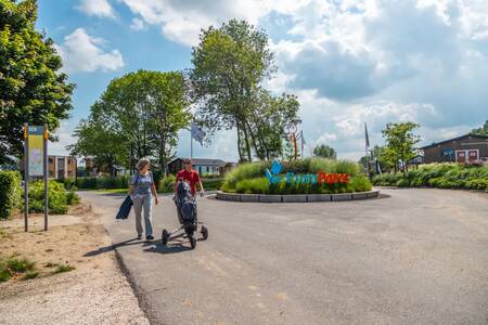 Couple with golf clubs walks at the entrance of holiday park EuroParcs Aan de Maas