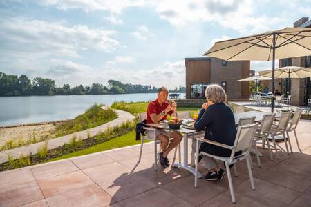 Couple in the garden of a holiday home on the water at the EuroParcs Aan de Maas holiday park