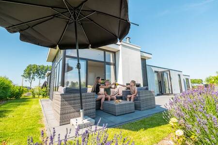 A family on a lounge set in the garden of a holiday home at the EuroParcs Bad MeerSee holiday park