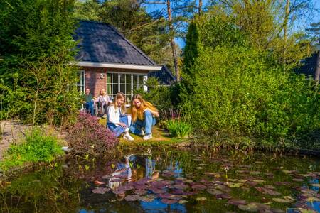 Family in the garden of a holiday home by the water at holiday park EuroParcs Beekbergen