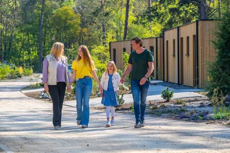 Family walks past holiday homes at holiday park EuroParcs Beekbergen