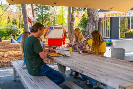 The family eats fries on the terrace of the restaurant at the EuroParcs Beekbergen holiday park
