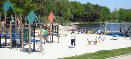 Children play in the playground next to the lake at the EuroParcs Brunssummerheide holiday park