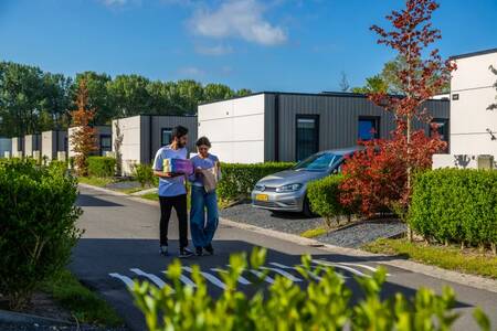 A couple walks along a road past holiday homes at the EuroParcs Buitenhuizen holiday park