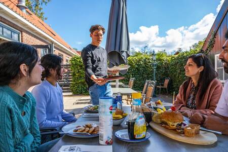 Family eating on the terrace of the restaurant at holiday park EuroParcs Buitenhuizen