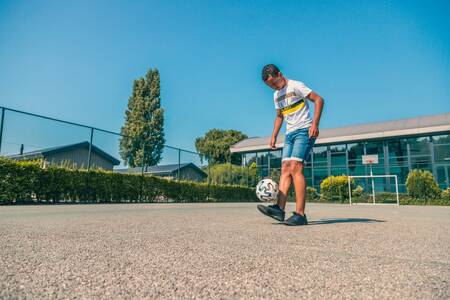 Boy playing football on the playing field of holiday park EuroParcs De Biesbosch