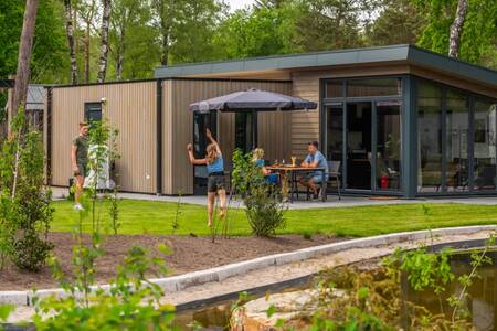 Family in the garden of a chalet at the EuroParcs De Hooge Veluwe holiday park