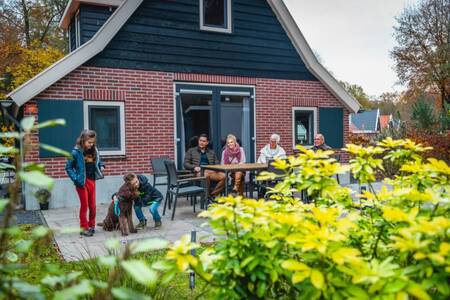 People in the garden of a detached holiday home at the EuroParcs De Hooge Veluwe holiday park