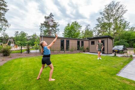 Children playing badminton in the garden of a holiday home at EuroParcs De Hooge Veluwe
