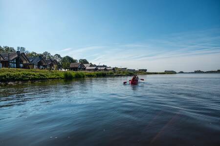 People canoeing past holiday homes at holiday park EuroParcs De IJssel Eilanden