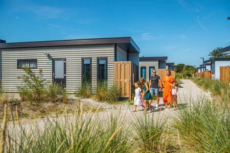 Family walks on a path past chalets at the EuroParcs De Koog holiday park