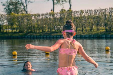 Children swim in the water at the beach of EuroParcs De Rijp holiday park