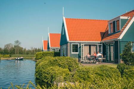 People in the garden of a detached holiday home on the water at holiday park EuroParcs De Rijp