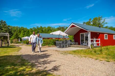 A couple walks past a chalet at the EuroParcs De Wije Werelt holiday park