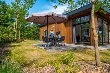 Family at the table in the garden of a holiday home at the EuroParcs De Wije Werelt holiday park